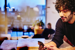 man sitting at table looking at smartphone