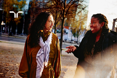 two women having a conversation while crossing a road