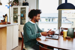 man sitting at dining room table working on laptop