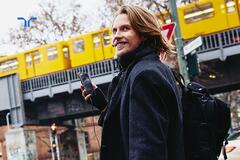 man listening to music on phone with train in the background