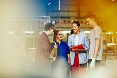 Four people standing next to a trolley in a warehouse, having a conversation and laughing.