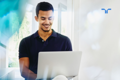 man smiling and working on a laptop