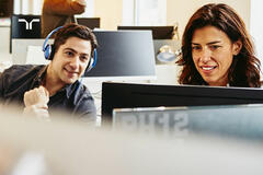 man with headphones and woman at computer