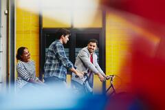 Group of colleagues (two males, one female) leaving work on bicycles.