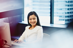 female working and smiling on laptop in an office