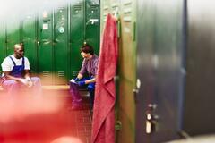 Two man having a conversation in a locker room.