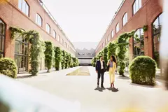 male and female walking outside between office buildings.
