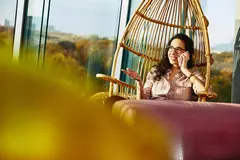 Womale sitting down while talking on the phone.
