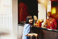 Man and woman working at a hotel reception desk helping a guest.