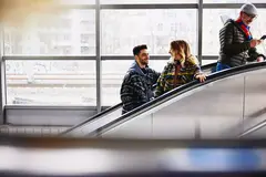 Smiling people on a escalator in a train station.
