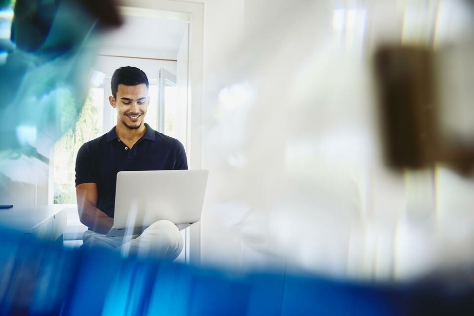 male sitting working on his laptop smiling