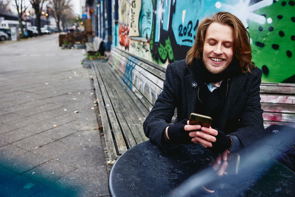 young man looking at his phone, smiling