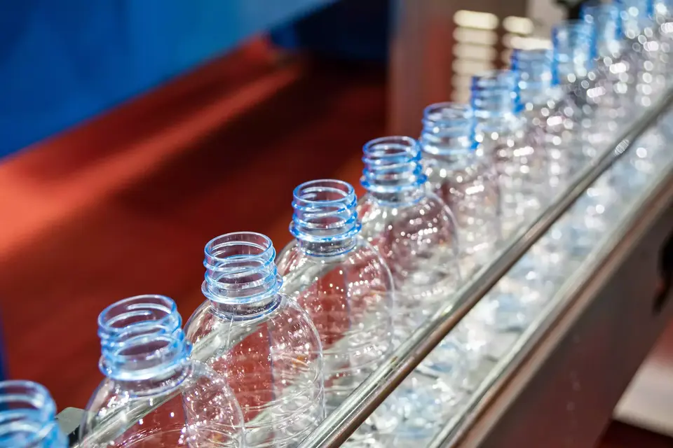 The PET bottles on the conveyor belt for filling process in the drinking water factory. The drinking water factory production process by automatic filling machine in the plant.